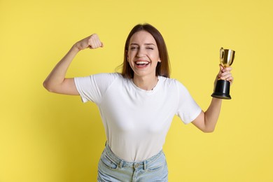 Photo of Happy winner with gold trophy cup on yellow background