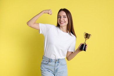 Photo of Happy winner with gold trophy cup on yellow background