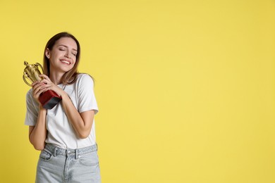 Photo of Happy winner with gold trophy cup on yellow background, space for text