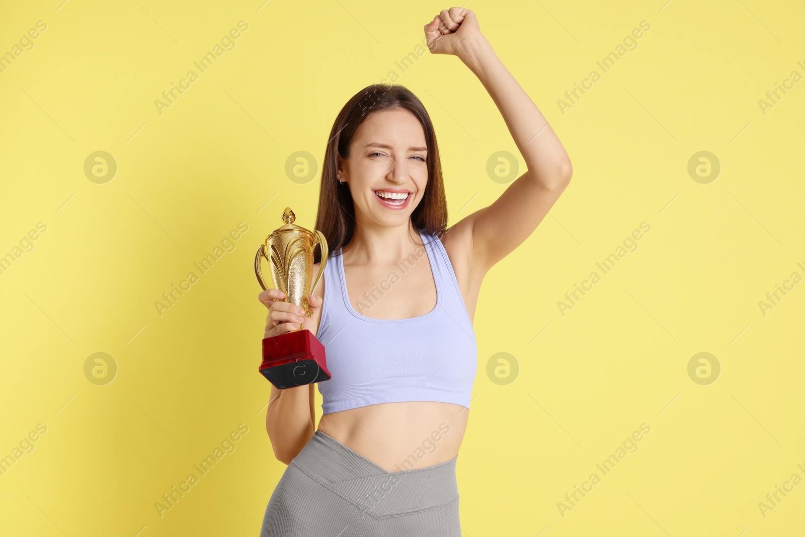 Photo of Happy winner with gold trophy cup on yellow background