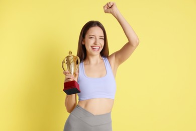 Photo of Happy winner with gold trophy cup on yellow background