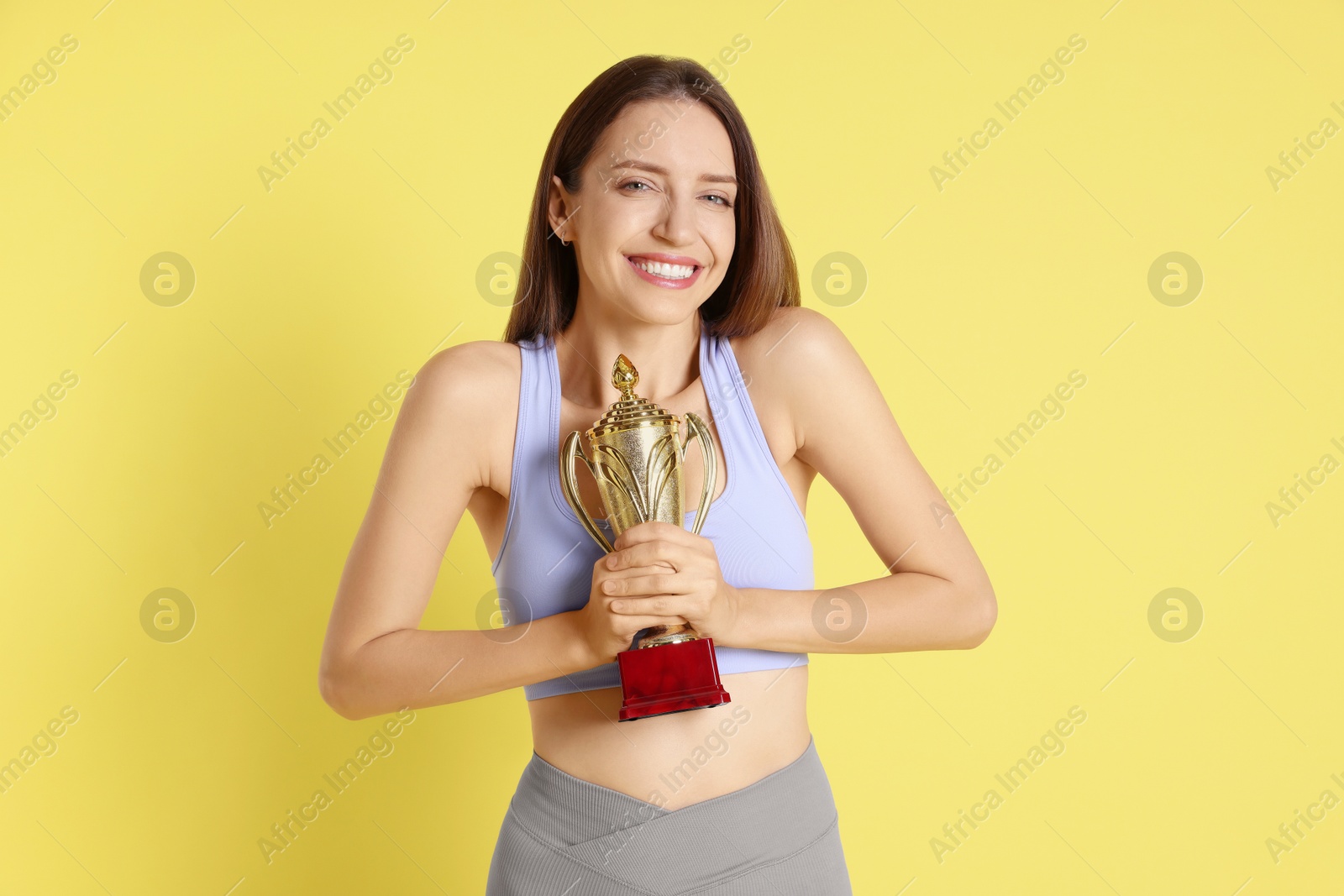 Photo of Happy winner with gold trophy cup on yellow background