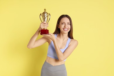 Photo of Happy winner with gold trophy cup on yellow background