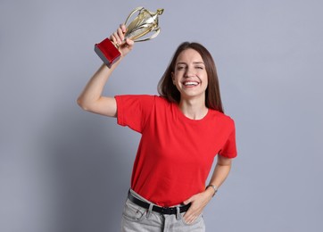 Happy winner with gold trophy cup on gray background