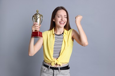 Photo of Happy winner with gold trophy cup on gray background