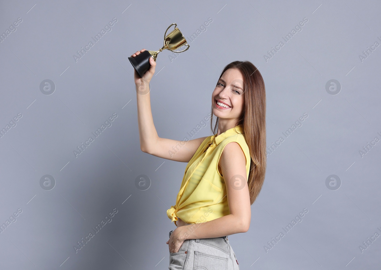 Photo of Happy winner with gold trophy cup on gray background