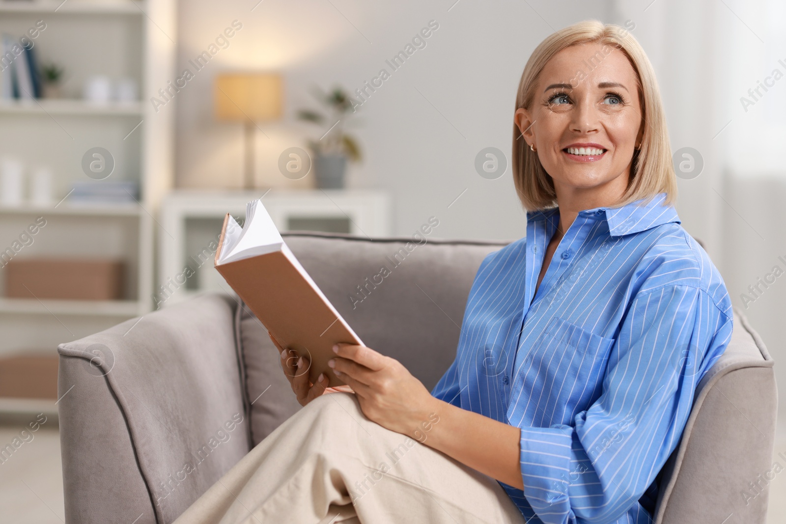 Photo of Portrait of smiling middle aged woman reading book at home