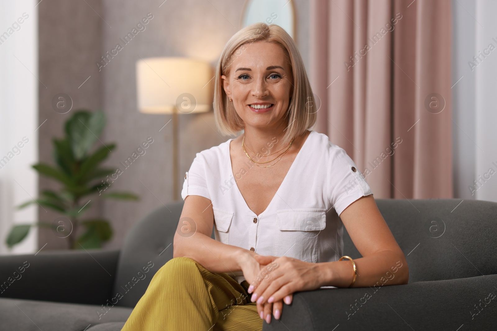 Photo of Portrait of smiling middle aged woman on sofa at home