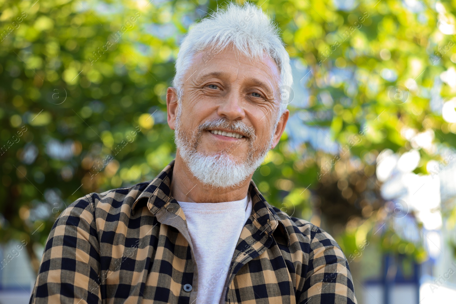 Photo of Portrait of smiling senior man in checkered shirt outdoors