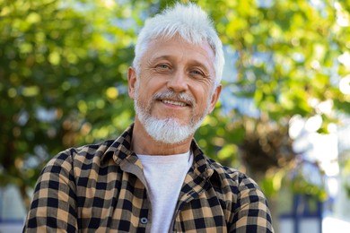 Photo of Portrait of smiling senior man in checkered shirt outdoors