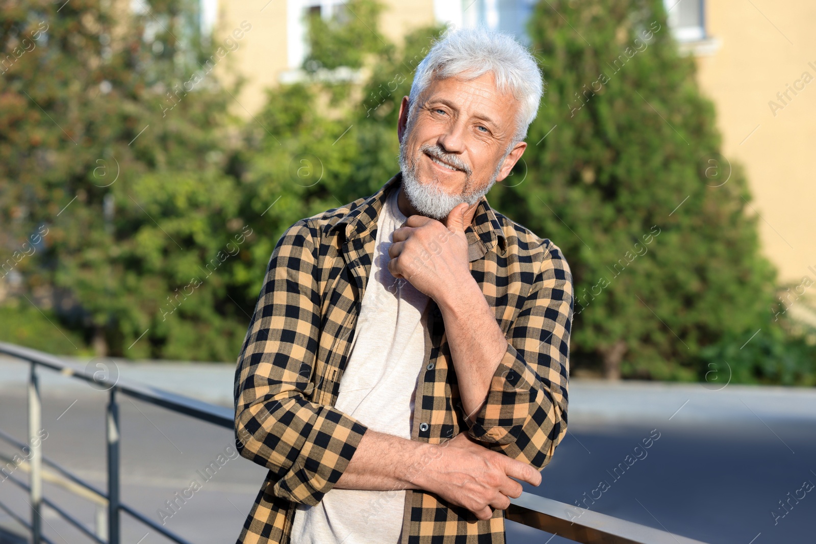 Photo of Portrait of smiling senior man in checkered shirt outdoors