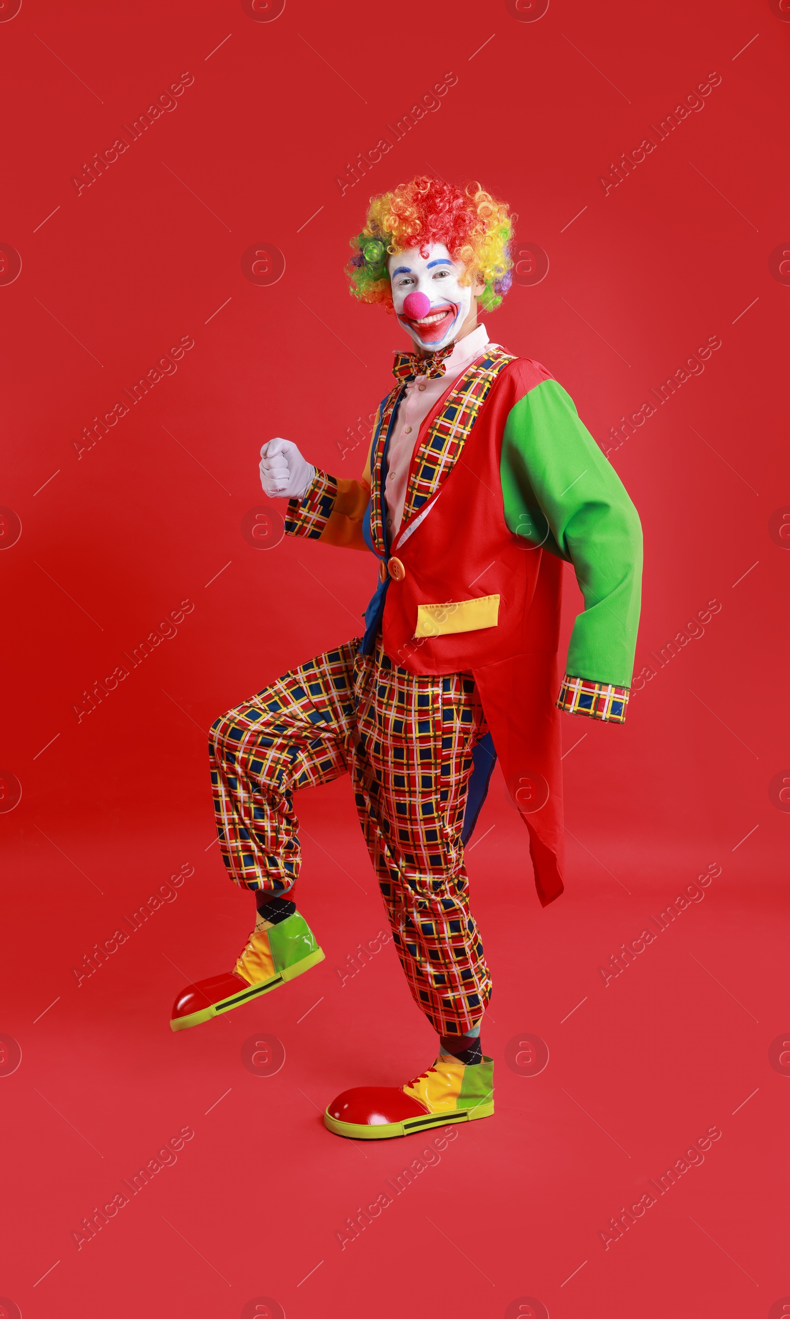 Photo of Portrait of happy clown on red background, space for text