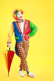 Clown with colorful umbrella on yellow background