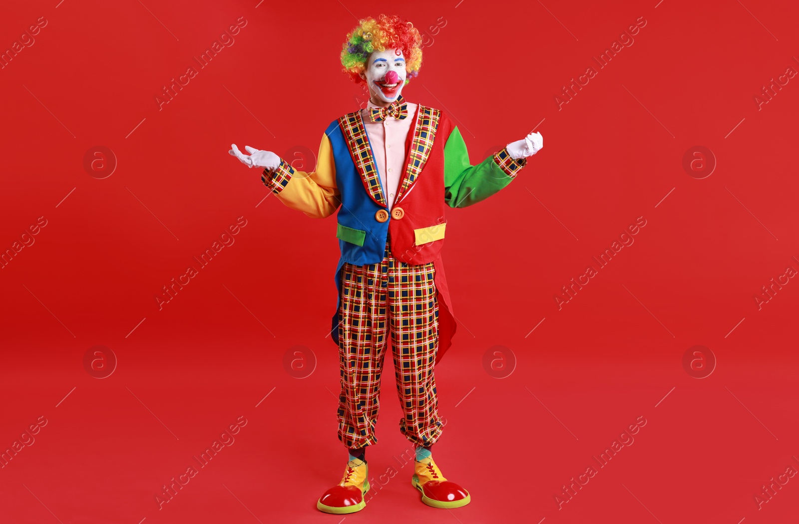 Photo of Portrait of happy clown on red background