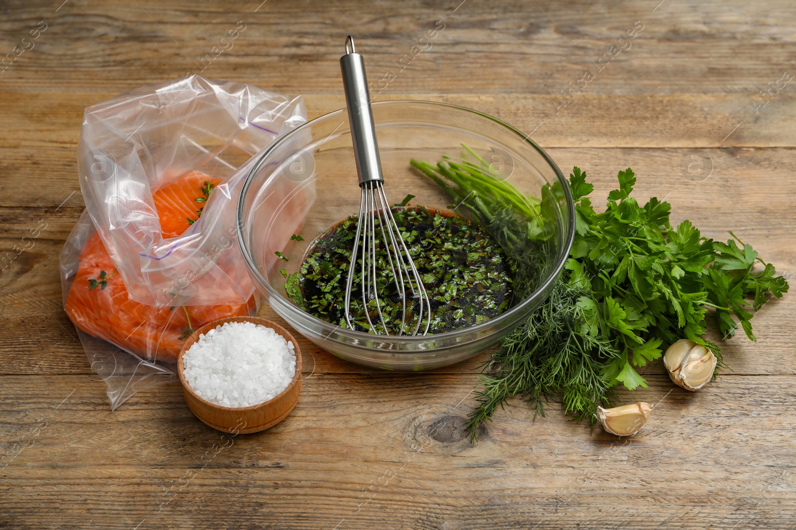 Photo of Soy marinade in bowl, whisk, salmon fillet and spices on wooden table