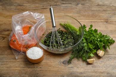 Photo of Soy marinade in bowl, whisk, salmon fillet and spices on wooden table