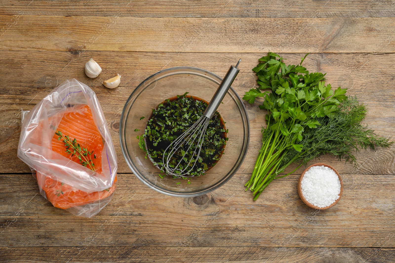 Photo of Soy marinade in bowl, whisk, salmon fillet and spices on wooden table, flat lay