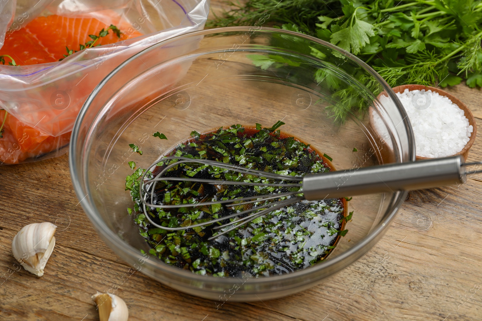 Photo of Soy marinade in bowl, whisk, salmon fillet and spices on wooden table closeup