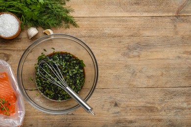 Photo of Soy marinade in bowl, whisk, salmon fillet and spices on wooden table, flat lay. Space for text