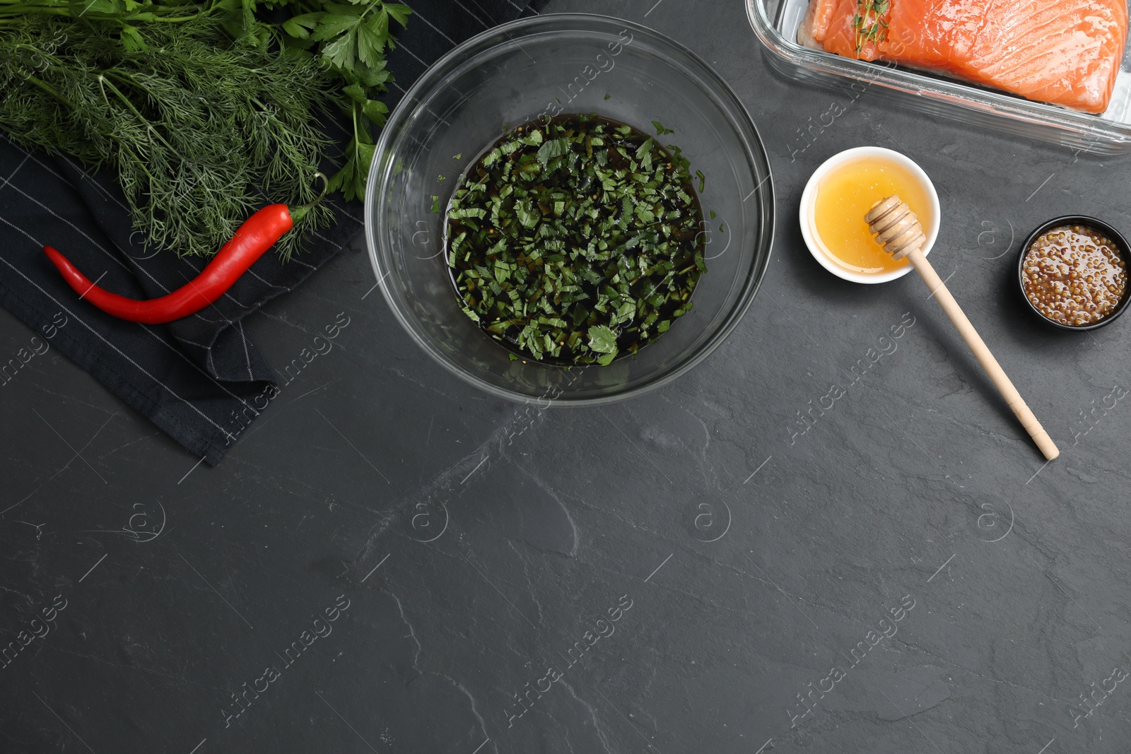 Photo of Soy marinade in bowl, salmon fillet and other products on dark gray textured table, flat lay. Space for text