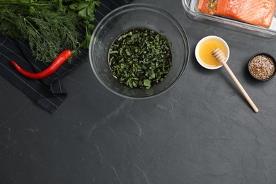 Photo of Soy marinade in bowl, salmon fillet and other products on dark gray textured table, flat lay. Space for text