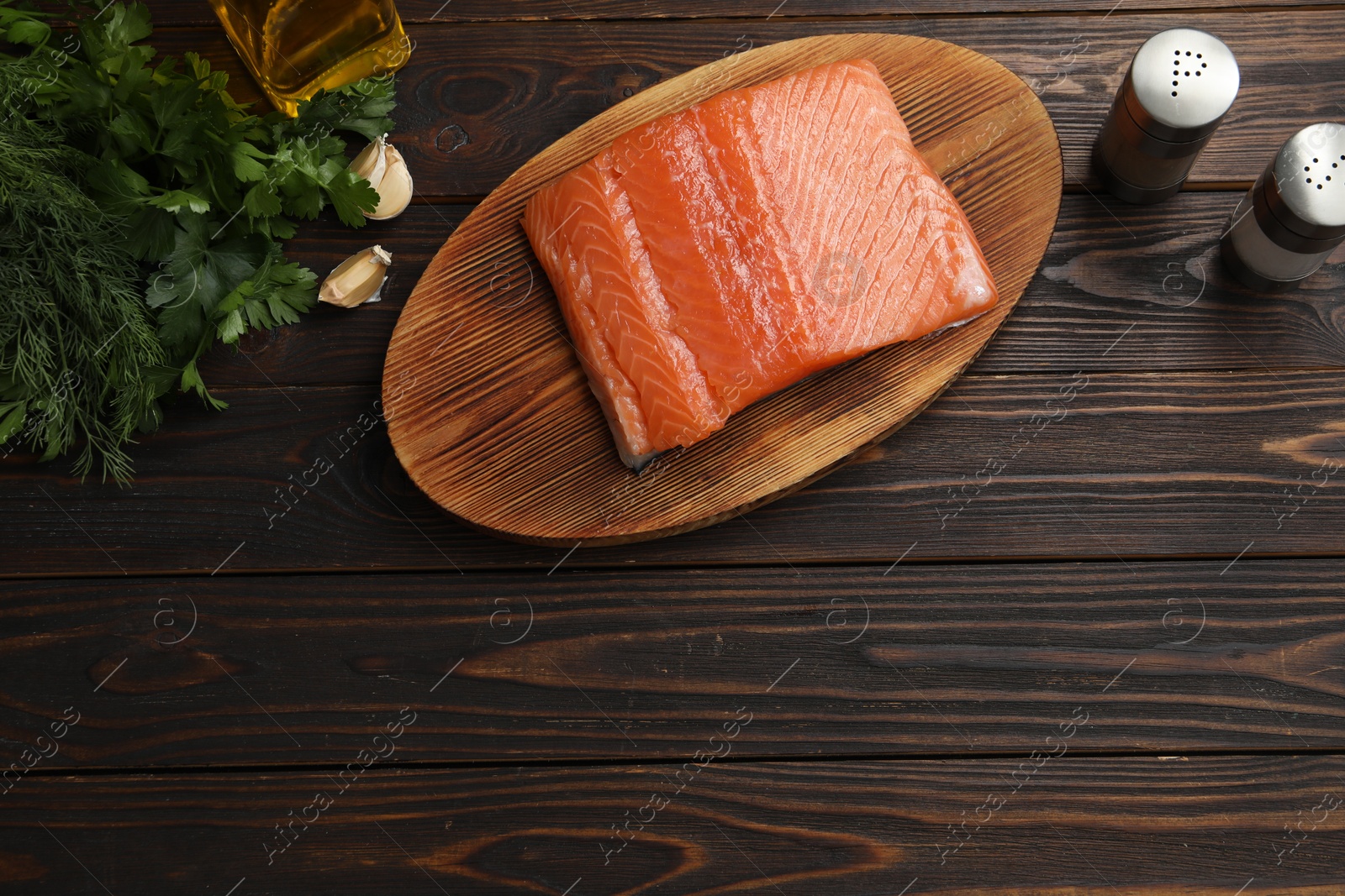 Photo of Salmon fillet, oil and spices on wooden table, flat lay. Space for text