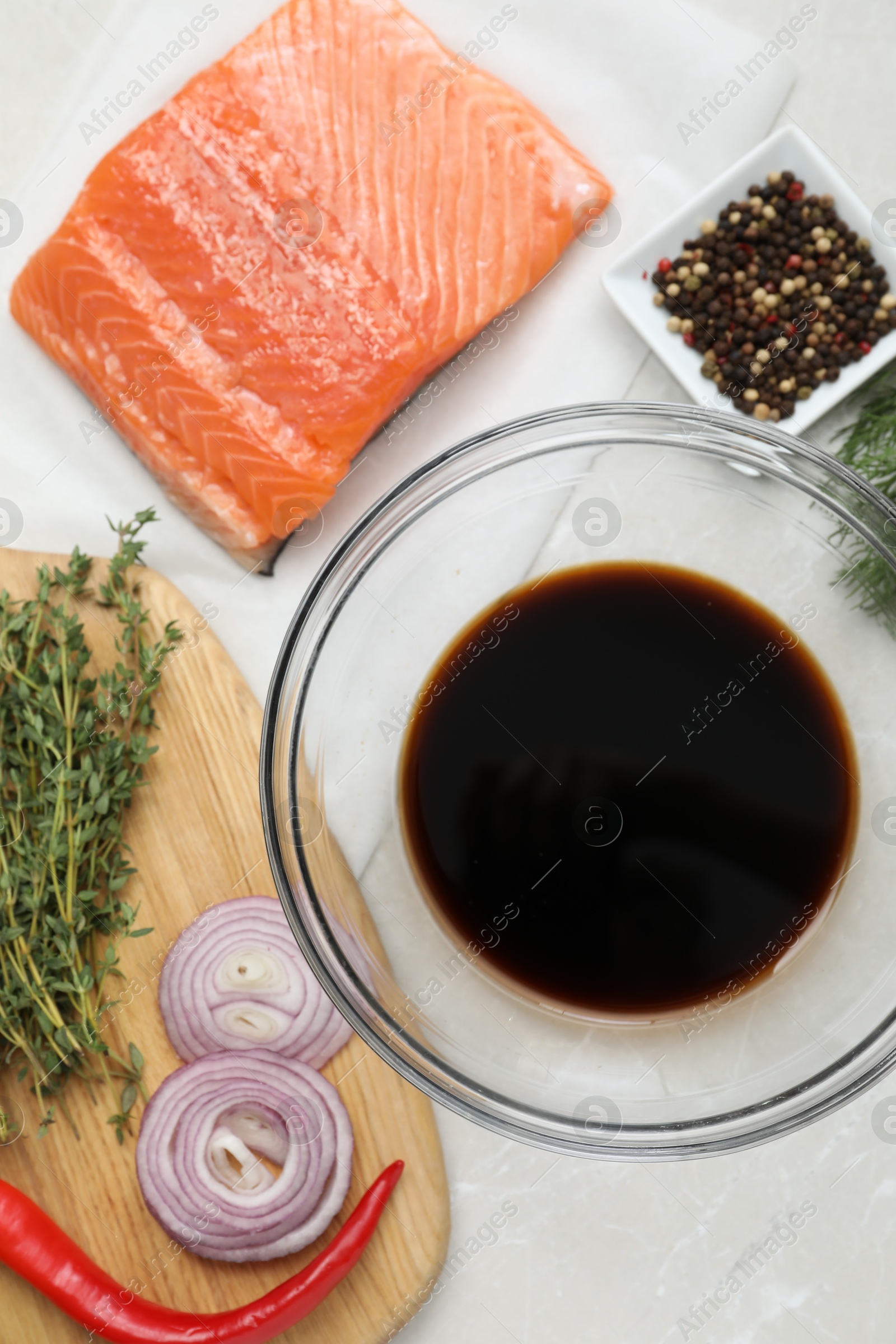 Photo of Soy sauce in bowl, salmon fillet and spices on gray marble table, flat lay