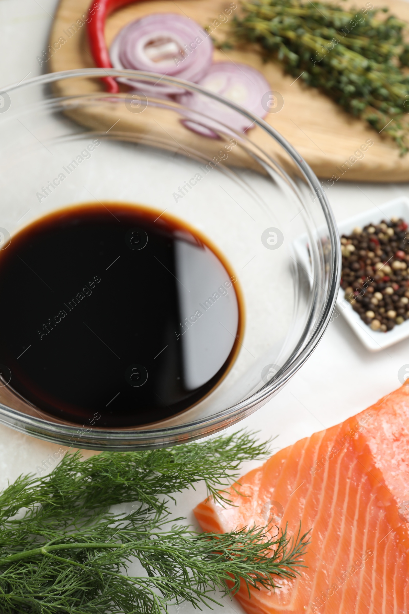 Photo of Soy sauce in bowl, salmon fillet and spices on gray marble table, closeup