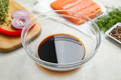 Photo of Soy sauce in bowl, salmon fillet and spices on gray marble table, closeup