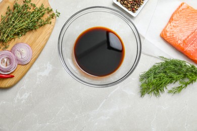 Photo of Soy sauce in bowl, salmon fillet and spices on gray marble table, flat lay