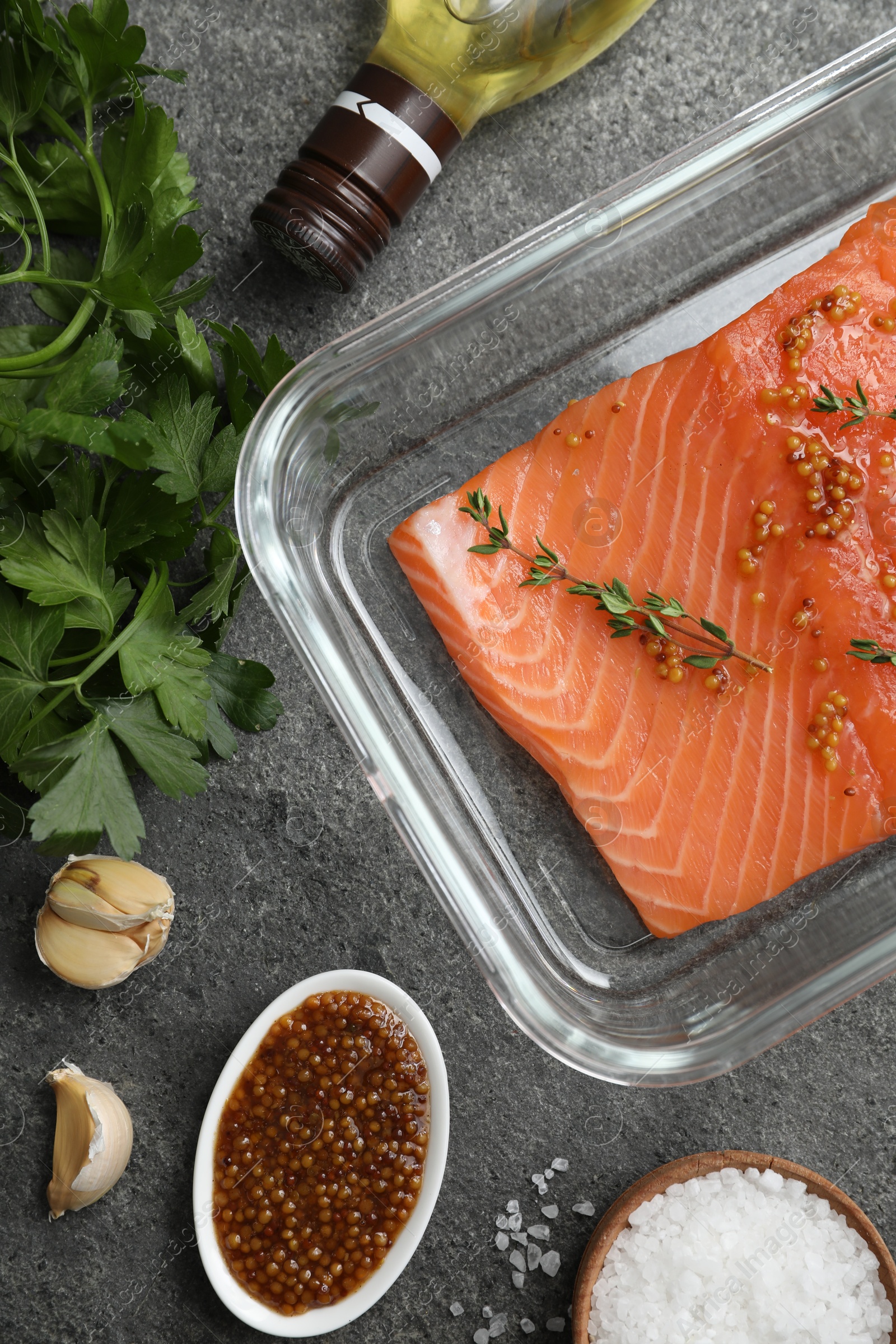 Photo of Salmon fillet with spices in dish and oil on gray textured table, flat lay