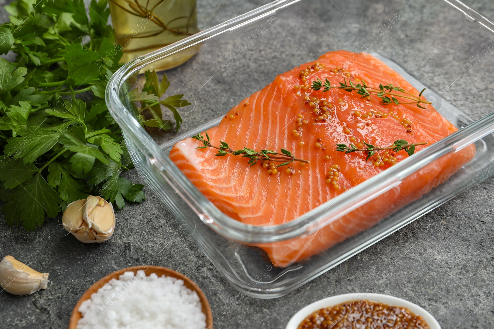 Photo of Salmon fillet with spices in dish on gray textured table, closeup