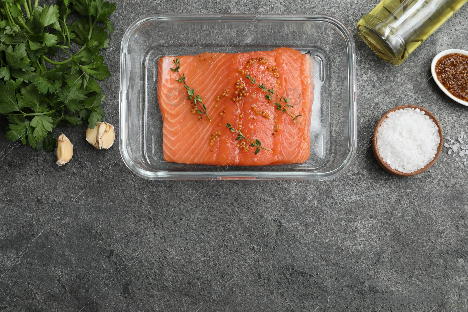 Photo of Salmon fillet with spices in dish and oil on gray textured table, flat lay. Space for text