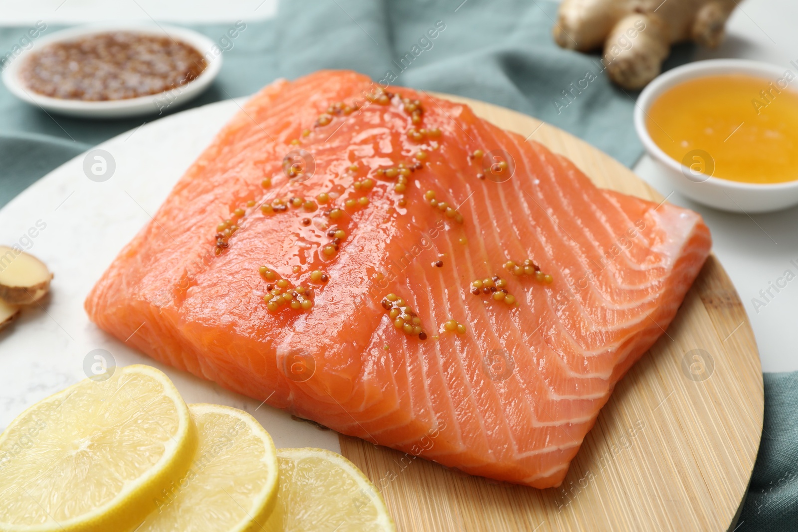 Photo of Salmon fillet with mustard and lemon slices on table, closeup