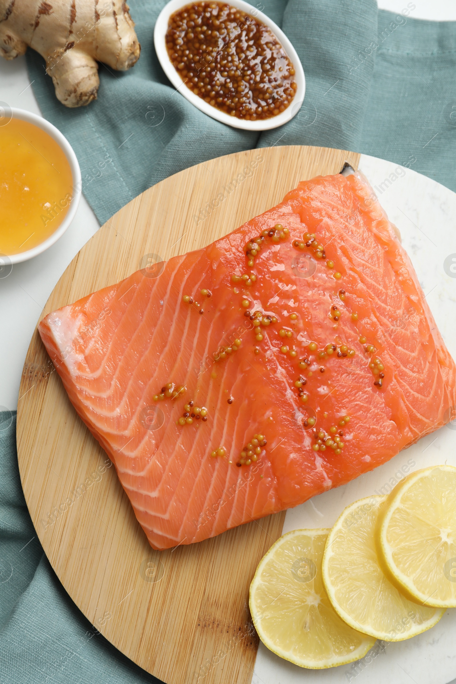 Photo of Salmon fillet with mustard, lemon slices, honey and ginger on table, flat lay