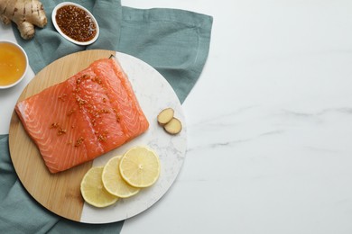 Photo of Salmon fillet with mustard, lemon slices, honey and ginger on white marble table, flat lay. Space for text