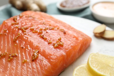 Photo of Salmon fillet with mustard and lemon slices on table, closeup