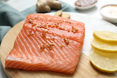 Photo of Salmon fillet with mustard and lemon slices on table, closeup