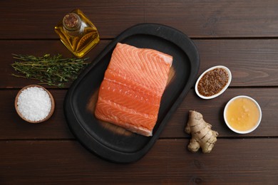 Photo of Salmon fillet, oil, spices and honey on wooden table, flat lay