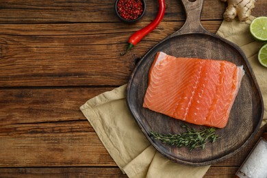 Photo of Salmon fillet, spices and lime on wooden table, flat lay. Space for text