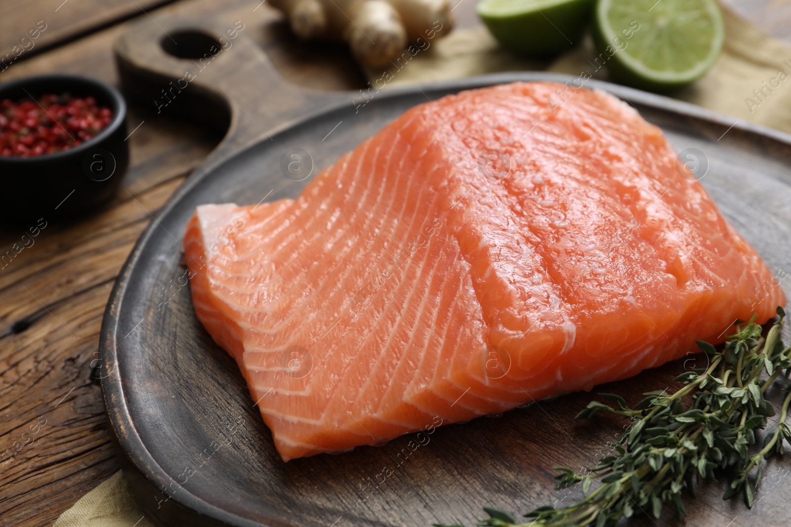 Photo of Salmon fillet and thyme on wooden table, closeup