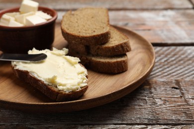 Photo of Fresh bread with butter and knife on wooden table, closeup