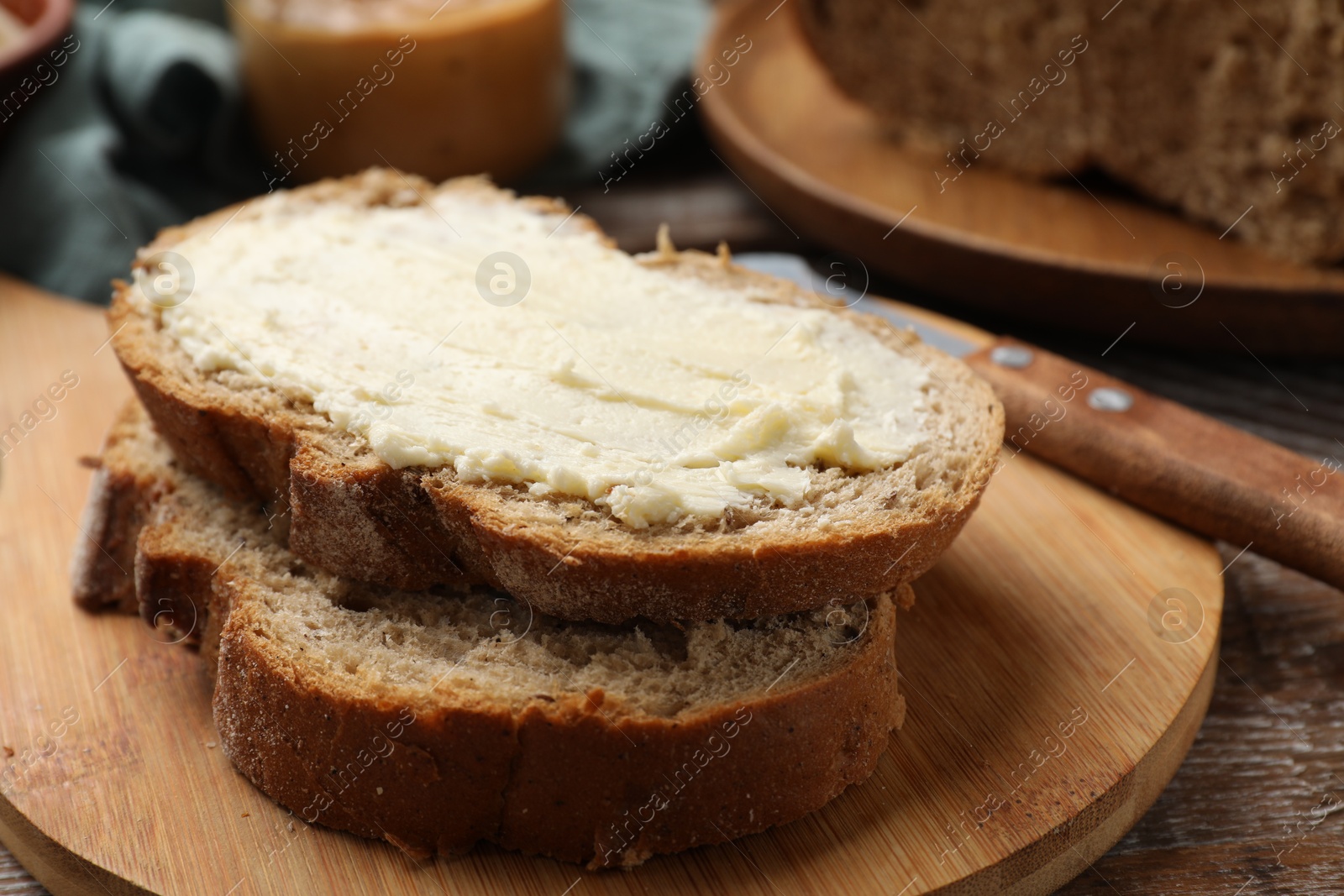 Photo of Fresh bread with butter on wooden table, closeup