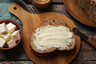 Photo of Fresh bread with butter and knife on wooden table, flat lay