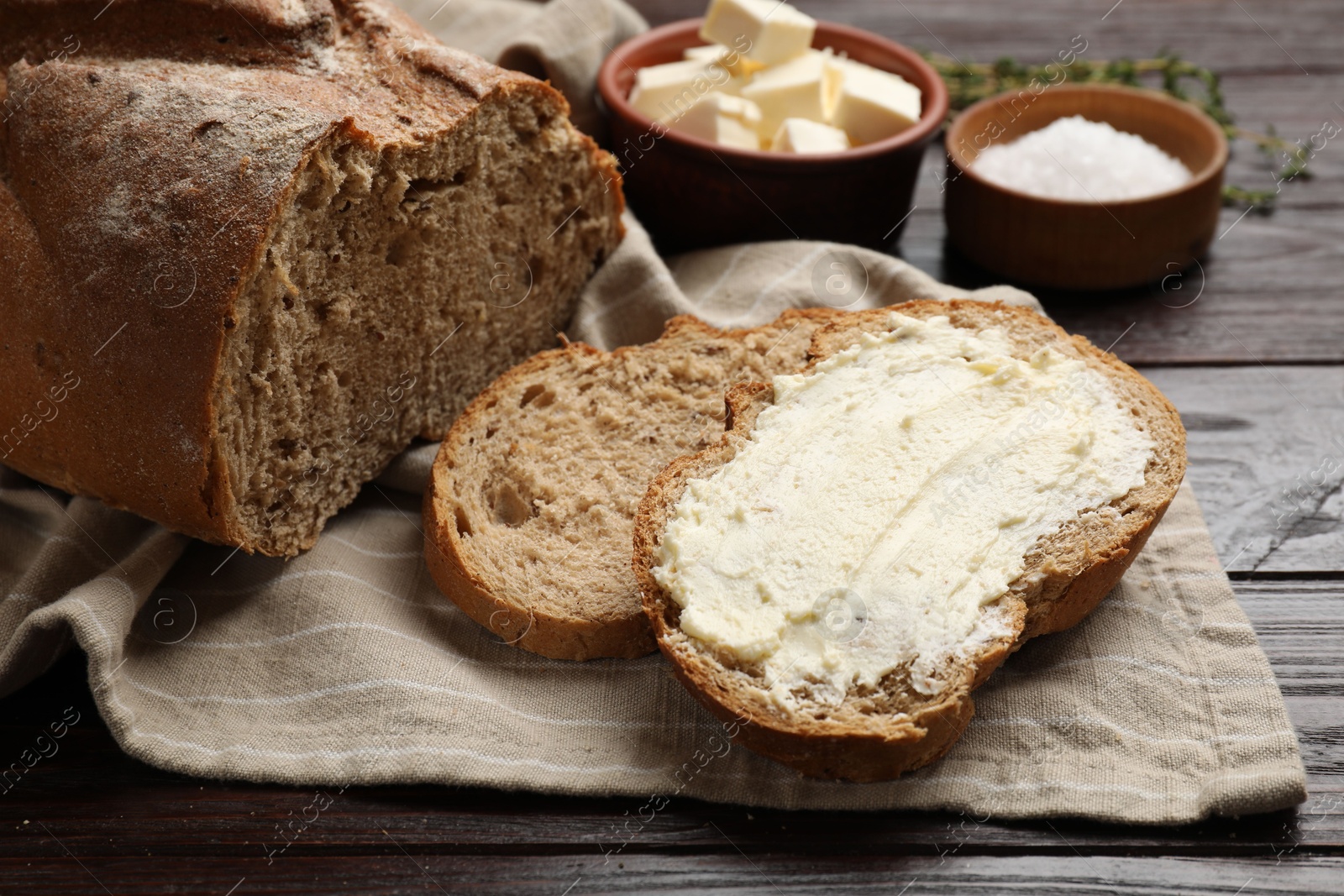 Photo of Fresh bread with butter on wooden table, closeup