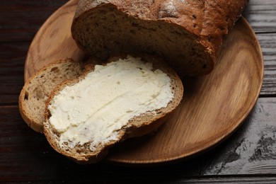 Photo of Fresh bread with butter on wooden table, closeup