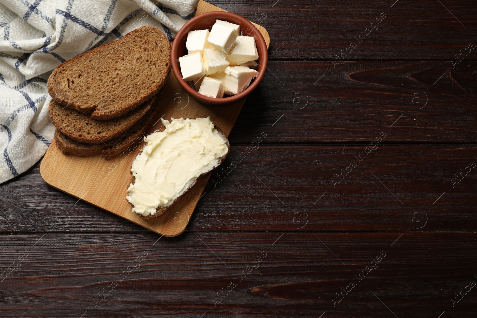 Photo of Fresh bread with butter on wooden table, top view. Space for text