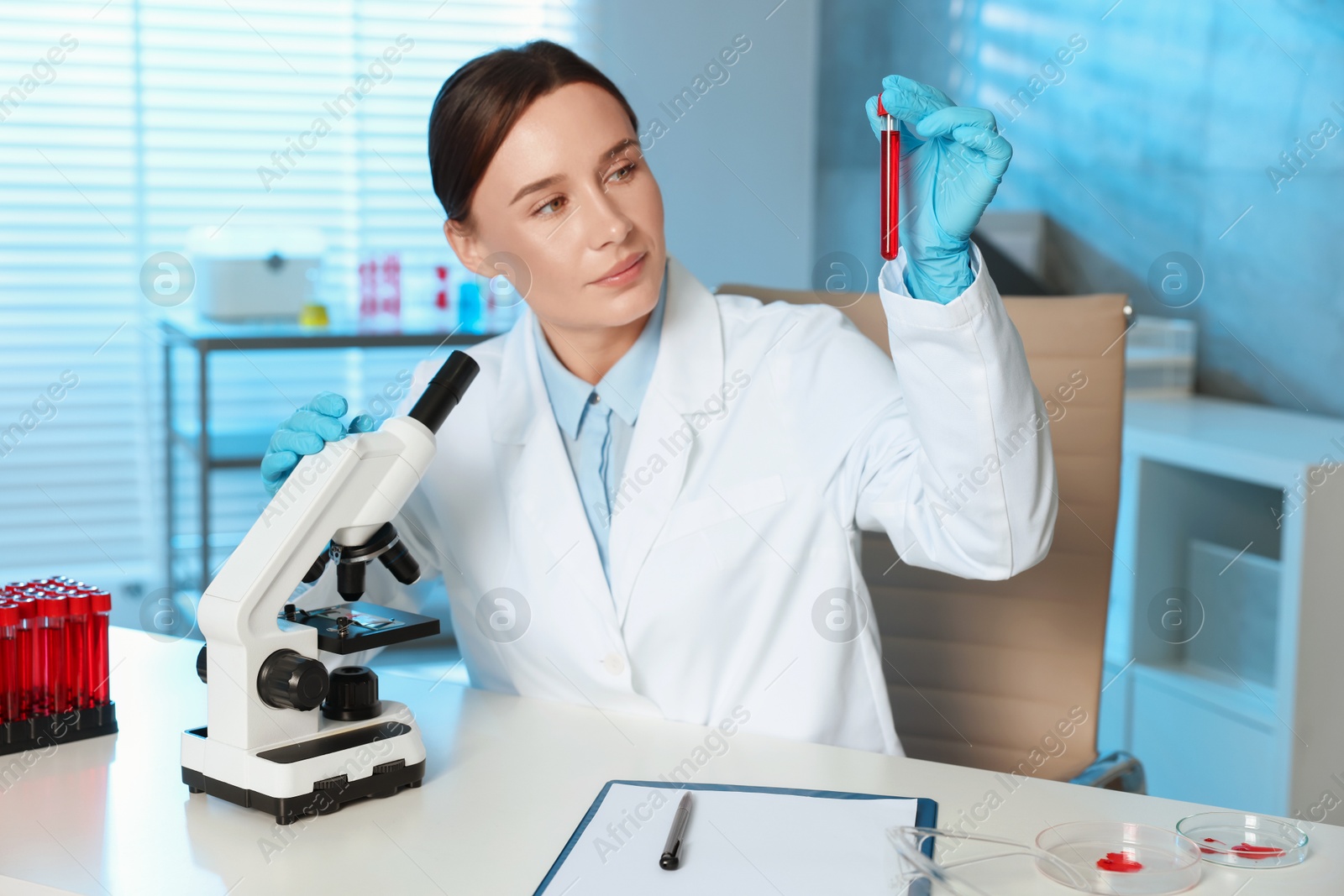 Photo of Laboratory testing. Doctor holding test tube with blood sample at table indoors