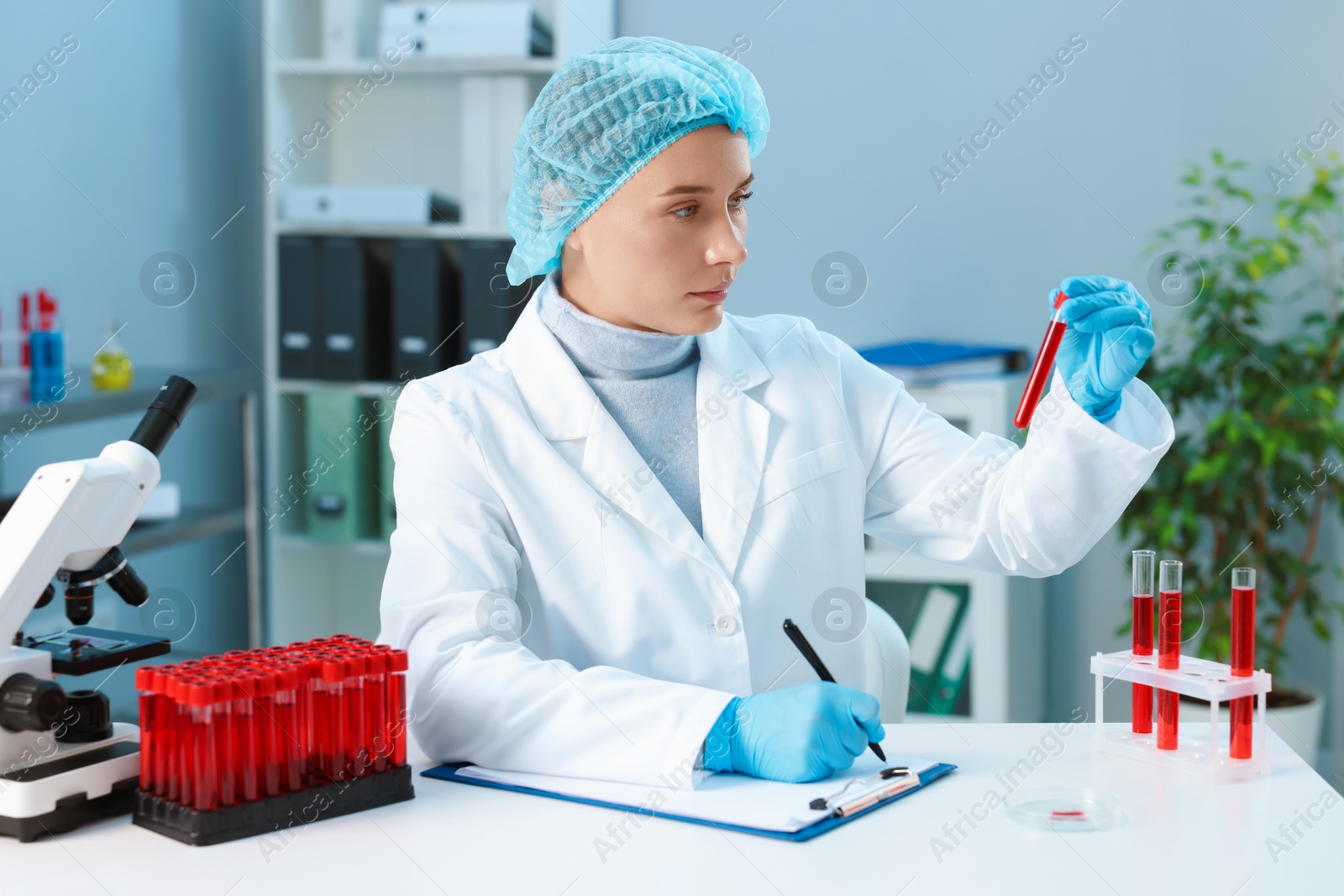 Photo of Laboratory testing. Doctor with blood sample taking notes at table indoors