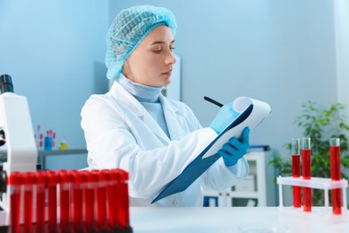 Photo of Laboratory testing. Doctor taking notes at table indoors